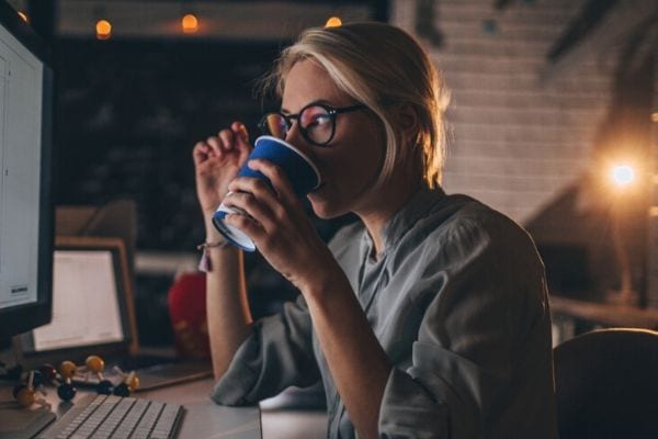 Woman at desk drinking a coffee